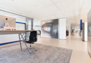 Modern kantoorinterieur aan de Barbara Strozzilaan met een minimalistisch bureau, bureaustoel en groot kunstwerk van een oog op de muur.